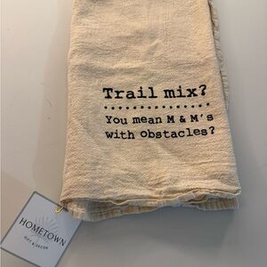 NWT  tan colored tea towel that says “trail mix? You mean m&ms with obstacles?”